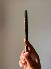 Load image into Gallery viewer, ide view of an oval black resin coaster, 0.8 cm thick, with the delicate edges of the hibiscus flower petals folding over onto the sides, creating a seamless and artistic design