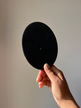 Load image into Gallery viewer, Opaque black resin surface on the back of an oval coaster, with a smooth and reflective finish under soft lighting